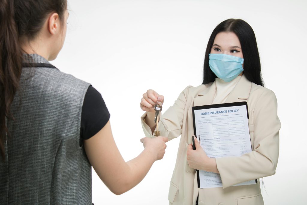 pexels-photo-7736037-7736037 Real estate agent in a face mask hands keys to a client, illustrating safe business practices.