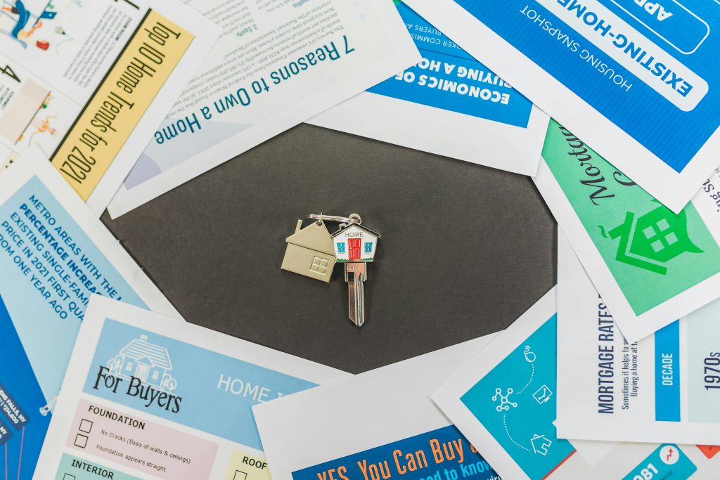pexels-photo-8293714-8293714 Overhead view of real estate brochures and house key, ideal for marketing.