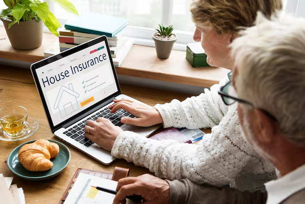 A couple sitting together at a table, using a laptop to search for house insurance options